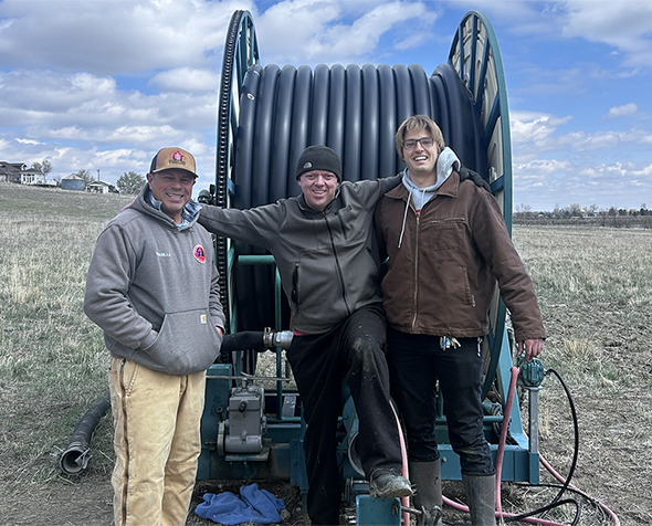 A farm employee, Justin Huff, and Uton Dellosso stand in front of the repaired farm equipment