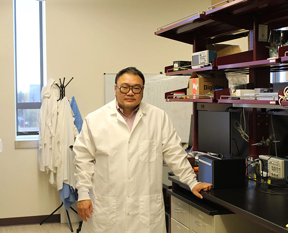Dali Sun stands by a table in his lab