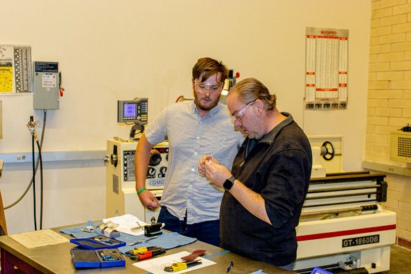 Justin Huff in the University of Denver Machine Shop, presenting a piece he built in the shop