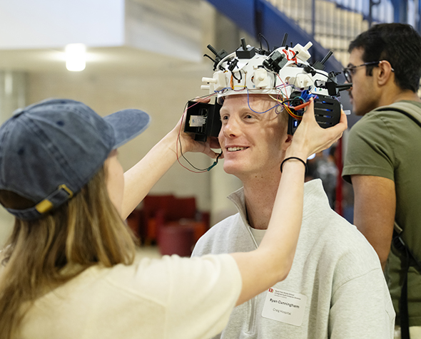 A student placing an EEG device on another student's head
