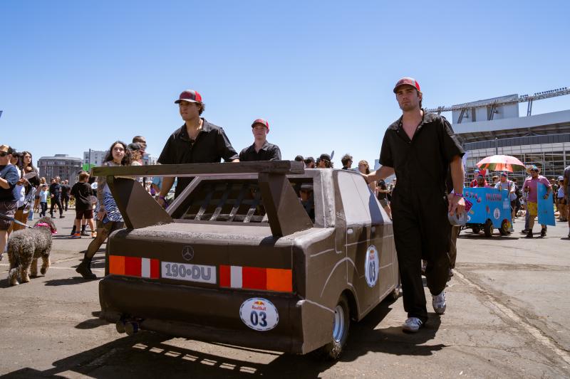Students with DU's Time Attack Racing Club roll their soapbox across the parking lot of Empower Field.