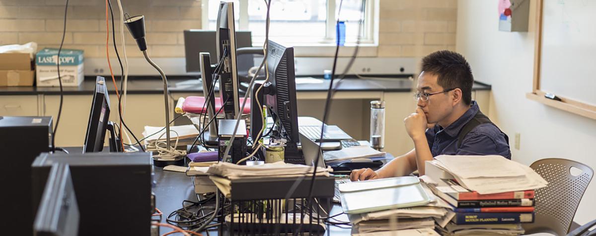 student at computer with multiple monitors
