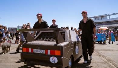 Students with DU's Time Attack Racing Club roll their soapbox across the parking lot of Empower Field.